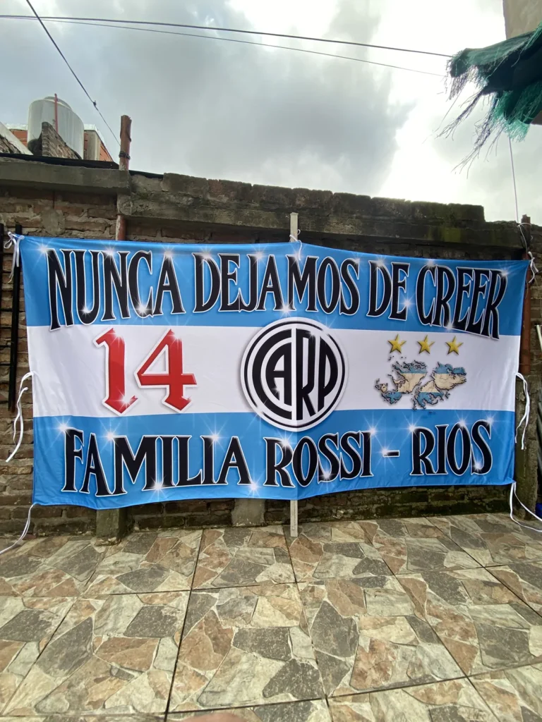 Bandera Nunca dejamos de creer familia Rossi Ríos